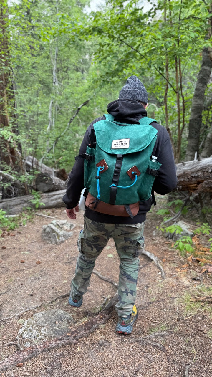 Hiker wearing the green Dakota backpack on a wooded trail